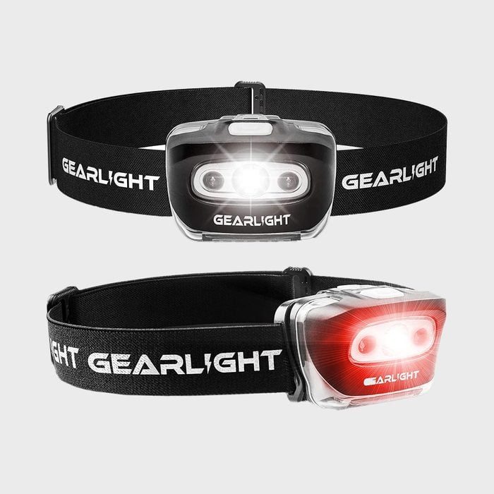 Headlamp emits bright white and red light, attached to an adjustable black strap labeled 