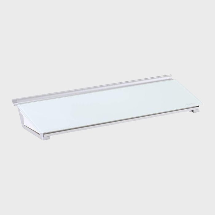 A sleek white shelf has a glass panel resting horizontally, supported by a metal frame, set against a plain gray background.