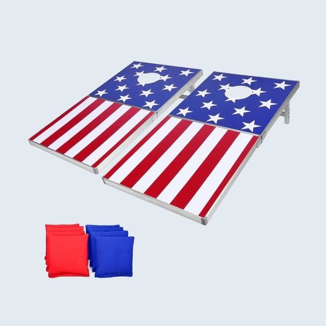 Bean bag boards, decorated with American flag designs, set for cornhole game; red and blue bean bags positioned nearby on a plain background.