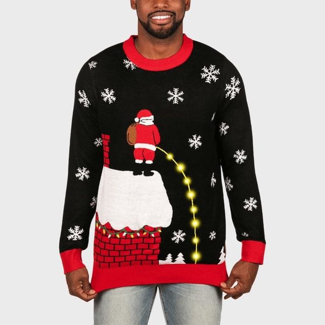 Man wears a black sweater showing Santa peeing on a rooftop, surrounded by snowflakes, against a plain background.