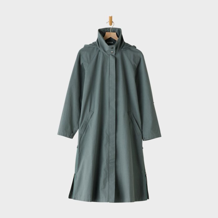 A long green coat hangs on a wooden hanger against a plain white background.