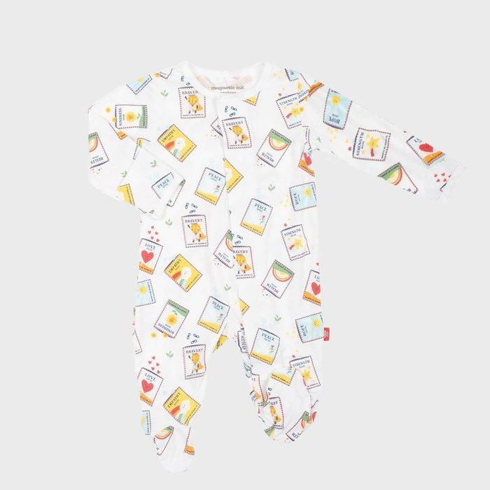 A white onesie displays colorful stamp patterns featuring fruits, rainbows, and hearts, set against a plain gray background.