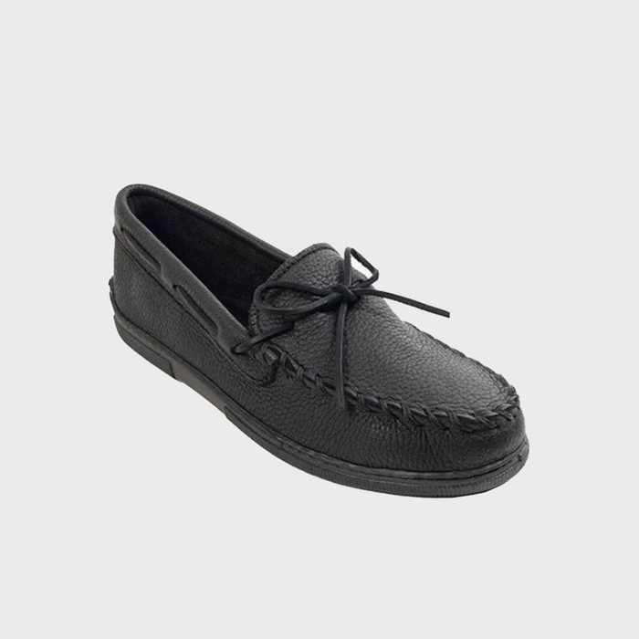 A black leather moccasin sits against a plain gray background, showcasing its textured surface and bow detail.