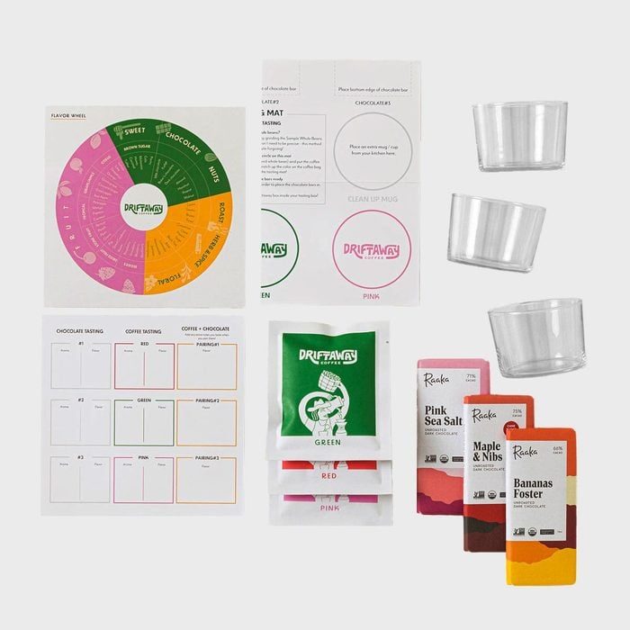 Assorted tasting kit, including flavor wheels, labeled packets, clear cups, chocolate bars, and instruction cards, arranged on a white background.