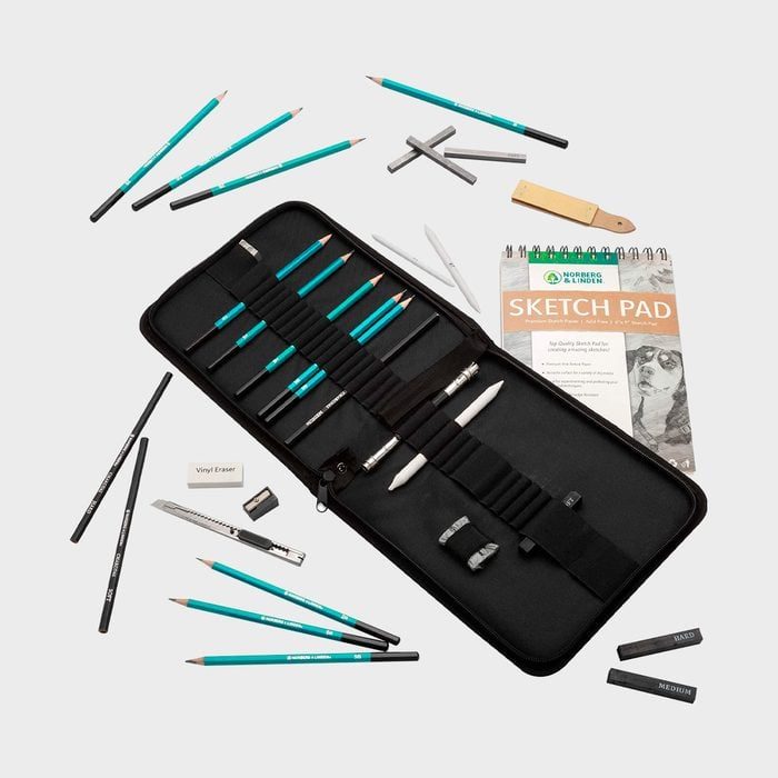 Art supplies neatly arranged; pencils and charcoal lay next to an open zipper case with compartments, alongside a sketch pad.