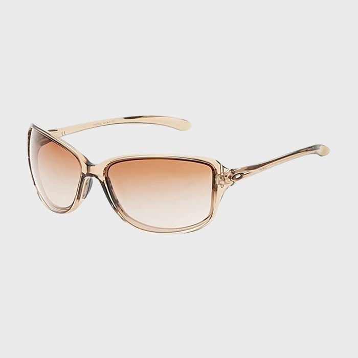 Sunglasses with amber-tinted lenses rest on a light gray background, featuring translucent beige frames and slightly curved arms.
