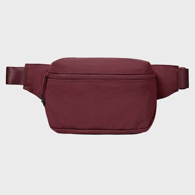 A maroon waist pack with a zipper is displayed against a plain gray background.