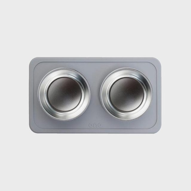 Two metal bowls sit in a gray rectangular mat with rounded corners, featuring the word 