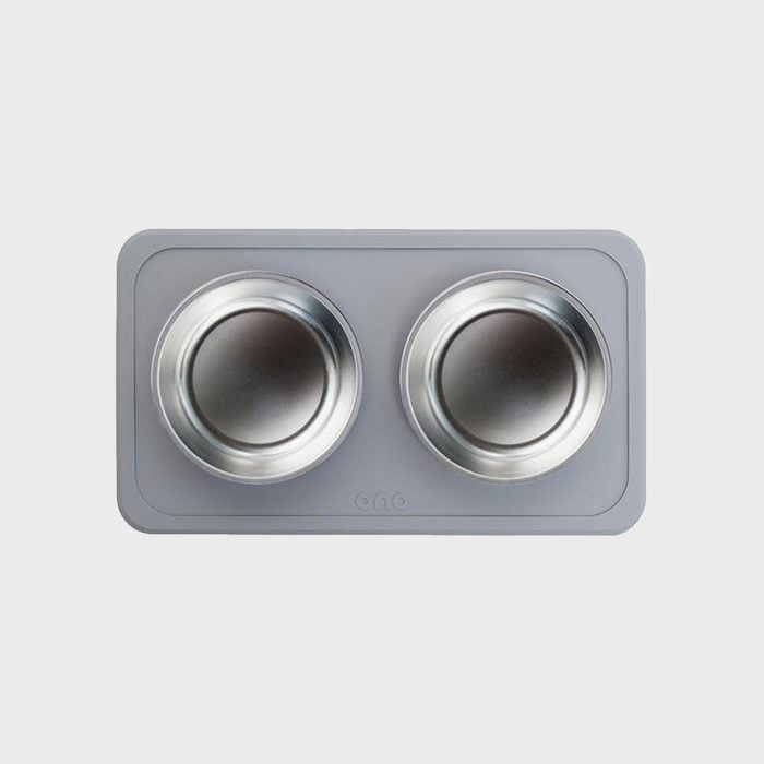 Two metal bowls sit in a gray rectangular mat with rounded corners, featuring the word 