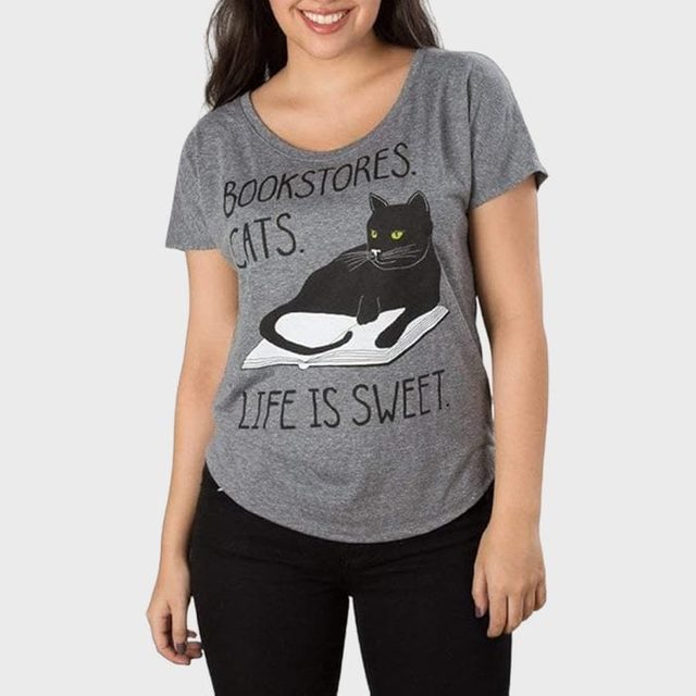 A person wears a gray T-shirt with a black cat illustration and the text 