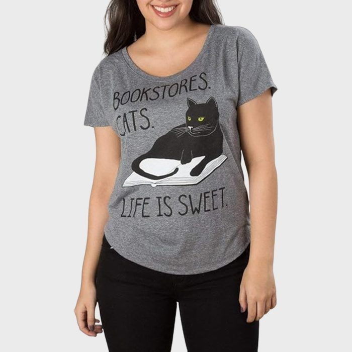 A person wears a gray T-shirt with a black cat illustration and the text 