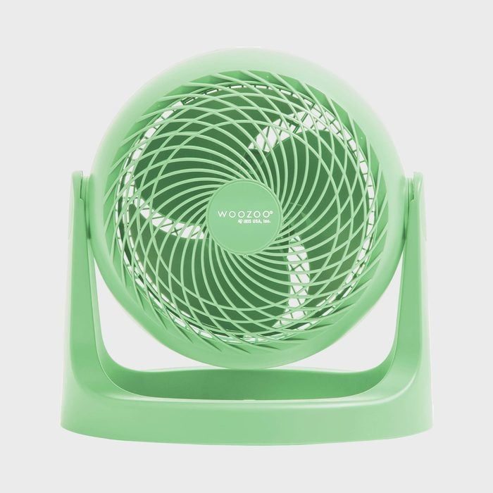 A green desktop fan stands still; features swirling grill design and 