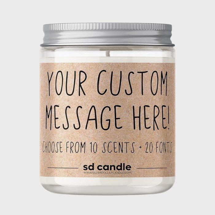 A jar candle displays customizable text options, promoting ten scents and twenty fonts, against a plain background.