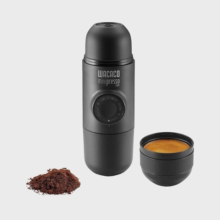 Portable espresso maker stands upright; brews coffee from grounds into detachable cup; gray background. Text: 