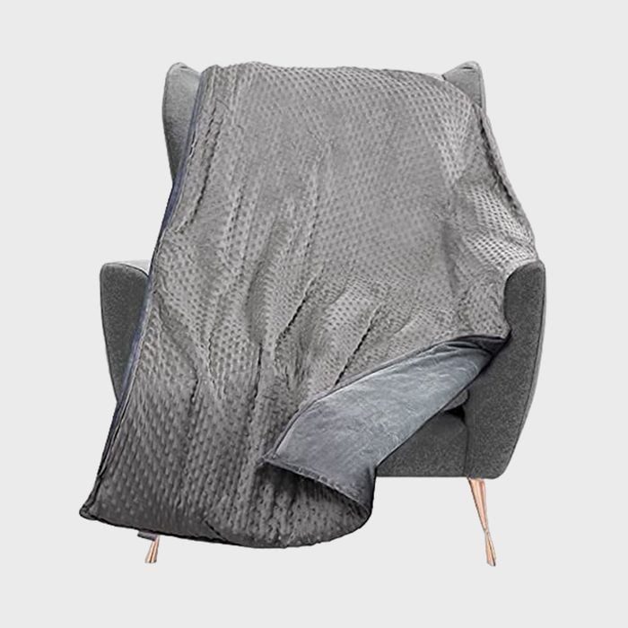 A textured gray blanket drapes over a cushioned chair against a plain white background.