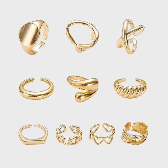 Gold rings, each unique in design, displayed on a plain light background, showcasing various shapes and styles in a symmetrical arrangement.