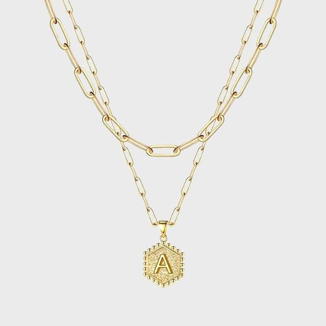 A gold necklace displays a pendant with the letter 