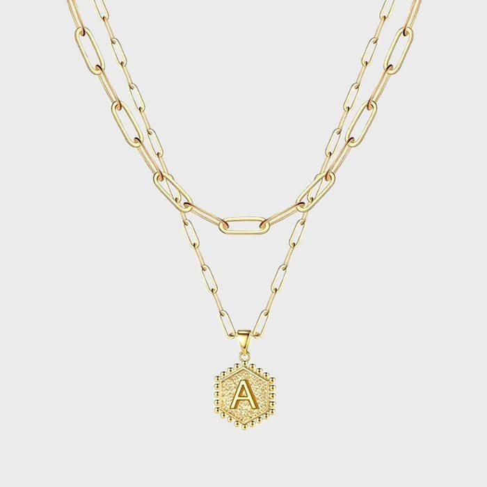 A gold necklace displays a pendant with the letter 