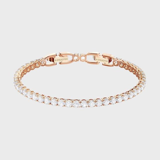 A rose gold bracelet with sparkling stones forms a delicate circle, set against a plain white background.
