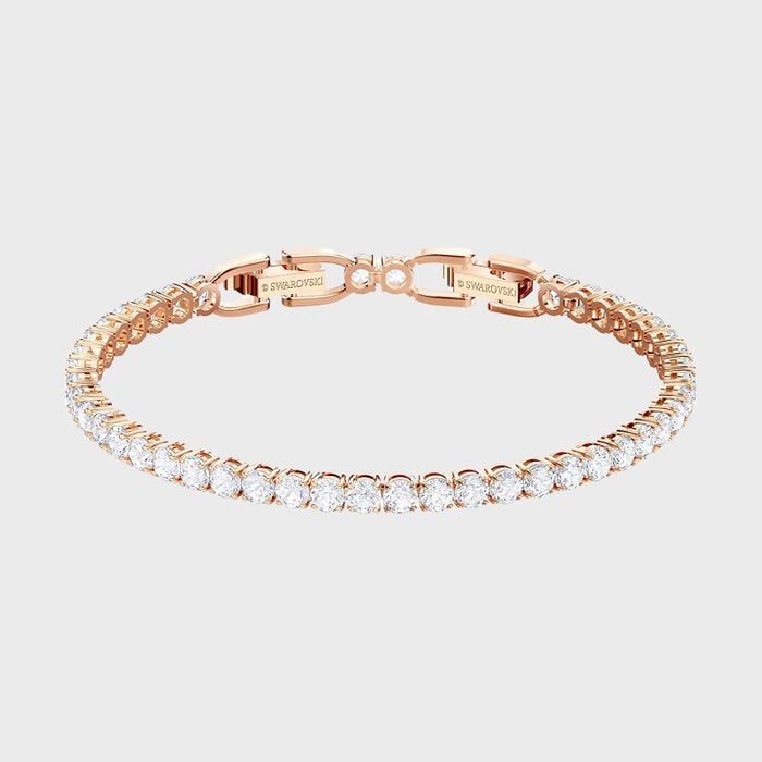 A rose gold bracelet with sparkling stones forms a delicate circle, set against a plain white background.