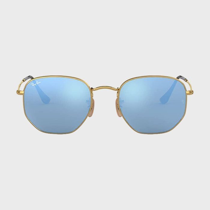 Gold-framed sunglasses reflect blue-tinted lenses, set against a plain gray background. The word 