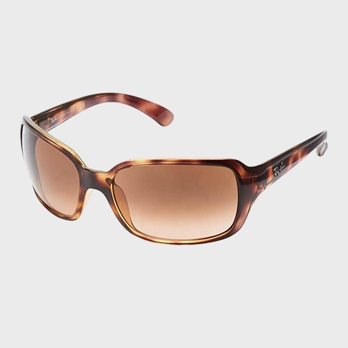 Sunglasses rest on a neutral background, featuring a tortoiseshell frame and brown-tinted lenses, with branding visible on the arms.
