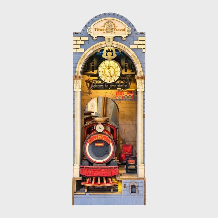 Train emerges from a stone archway under a clock; sign reads 