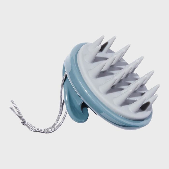 Spiked scalp massager resting on a white background with a looped cord attached to the handle.