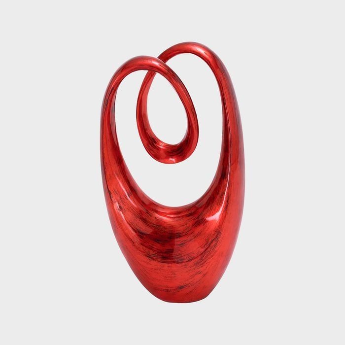 Red abstract sculpture stands with swirling loops against a plain white background.