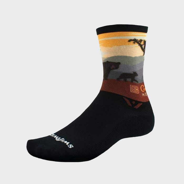 Sock displays mountain scene with bears against sunset hues; black foot section. Text reads: 