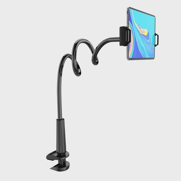 Tablet held by a flexible, spiraled arm attached to a desk clamp, against a plain gray background.