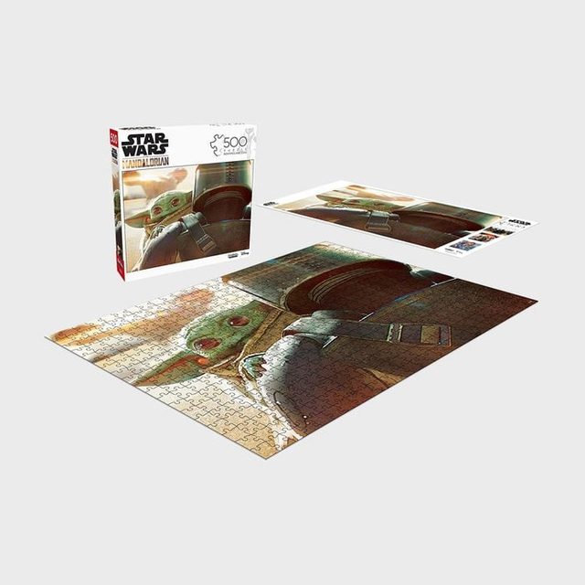 Puzzle showing a small creature in a robe sits completed on a table; box and poster of image nearby. Text: 