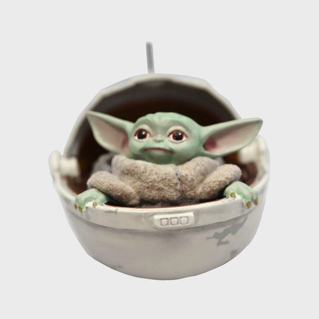A small green alien figurine rests comfortably inside a spherical pod, surrounded by a gray background.