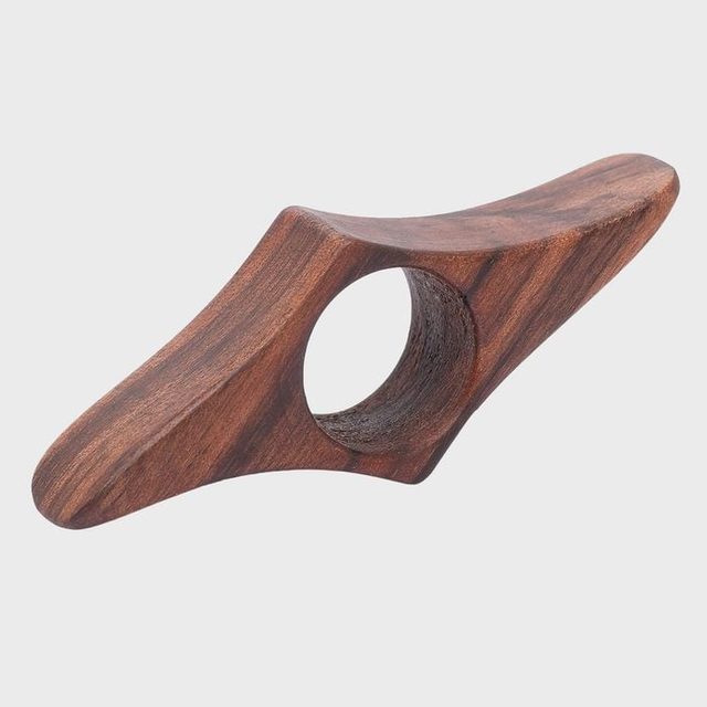Wooden object featuring a central hole, possibly a handle or tool, displayed against a plain background.