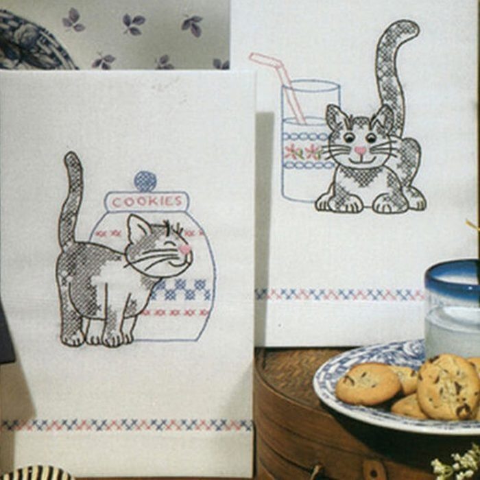 Two towels feature cat drawings; one stands before a cookie jar labeled 