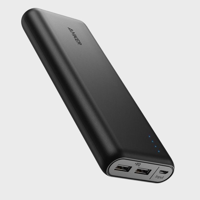 A black portable power bank displays two USB ports and four indicator lights against a plain gray background.