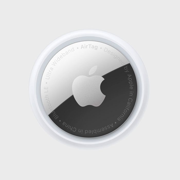 A round silver AirTag displays an Apple logo, encircled by text about design and assembly, against a plain white background.