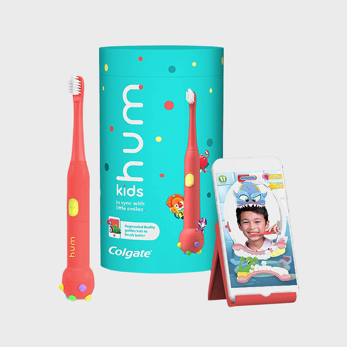 Toothbrush stands beside a colorful box; a smartphone displays a child using an augmented reality app. Theme: children's dental care. Text: 