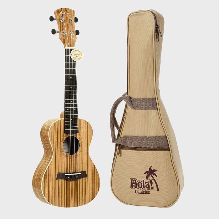 Ukulele stands upright next to a beige carrying case with 