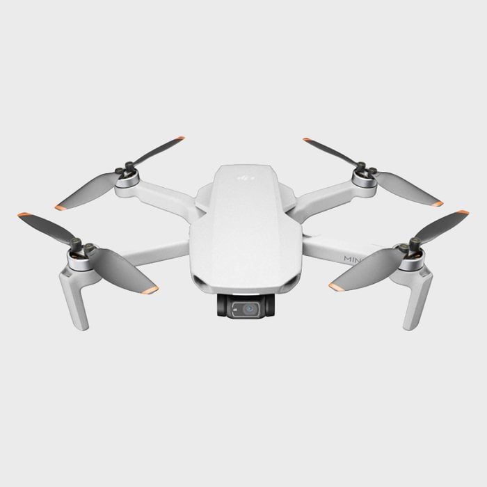 A small quadcopter drone with four propellers is hovering against a plain white background.