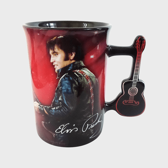Mug displays a person in a leather jacket; handle shaped like a guitar. Red background features stars. Signature reads 