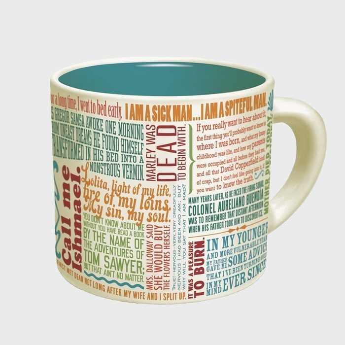 A ceramic mug displays colorful, overlapping famous literary quotes. The background is cream, and the interior is light blue, creating a vibrant, textual design.