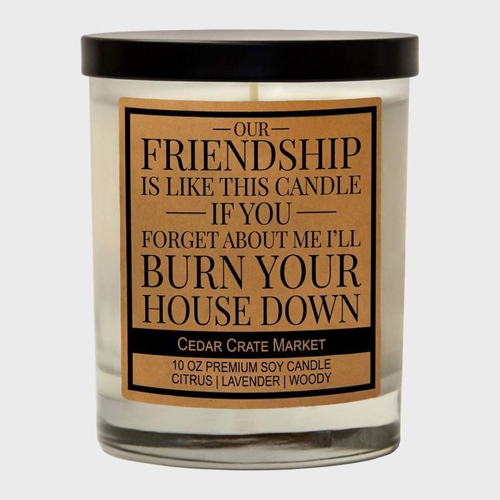 Candle displays humorous text about friendship, warning against forgetfulness. It suggests a playful threat in a minimalist setting, labeled 