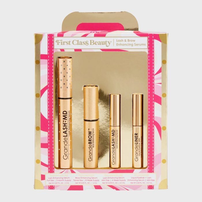 Set of four gold beauty serums displayed vertically, labeled GrandeLASH and GrandeBROW, in a decorative pink and gold box.