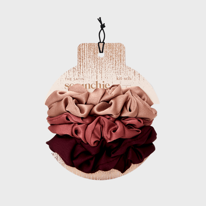 Scrunchies displayed in a set of blush, pink, and burgundy hues, attached to a cardboard packaging with 
