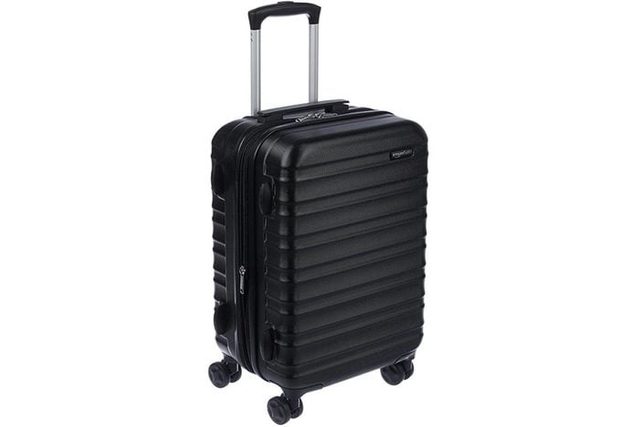 A black hard-shell suitcase stands upright, featuring four wheels and a telescopic handle, set against a plain white background.