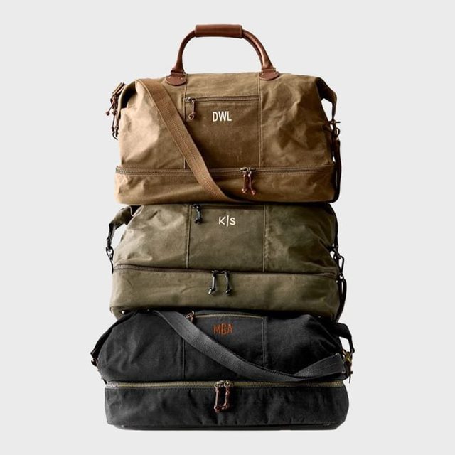 Three duffel bags stacked vertically; brown, green, and black. Brown leather accents and embroidered letters 
