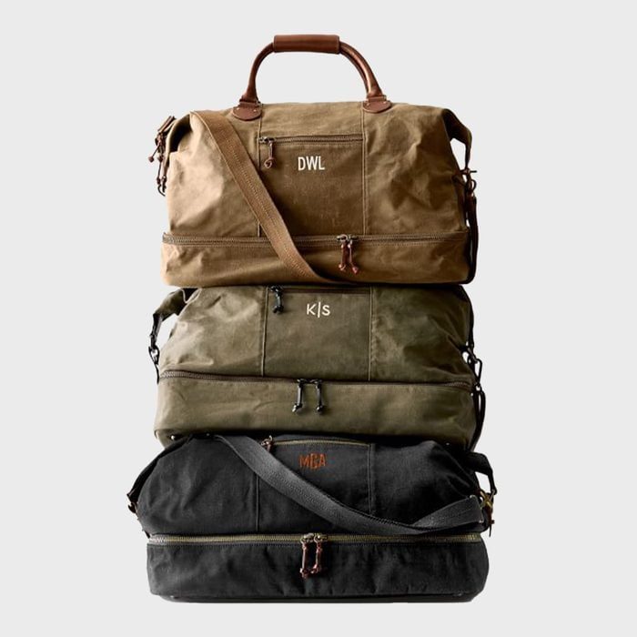 Three duffel bags stacked vertically; brown, green, and black. Brown leather accents and embroidered letters 