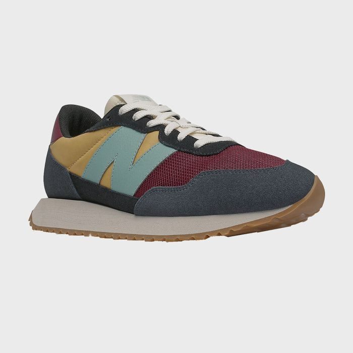 Sneaker with multi-colored panels rests on a white background; features include white laces, light blue logo, and brown sole.