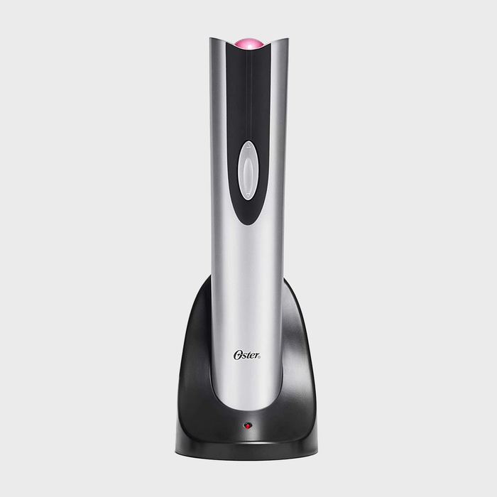 Electric wine opener standing upright on a black charging base with a metallic silver body in a plain gray background. 